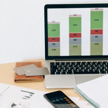 Laptop displaying financial chart alongside documents and credit cards on desk.