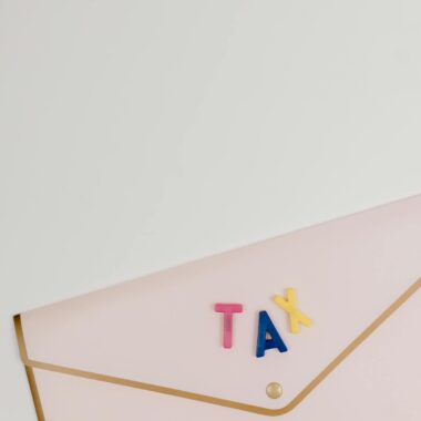 Pink envelope with TAX letters arranged on top, symbolizing tax-related themes.