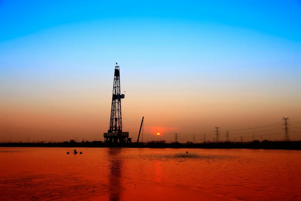 Oil rig silhouette at sunset over water.